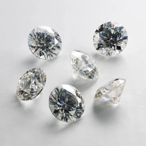 Seis diamantes redondos lapidados sobre superfície branca, destacando brilho e transparência