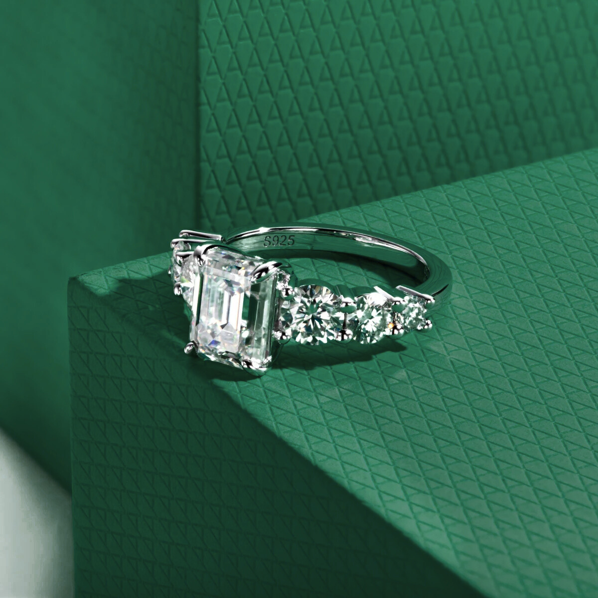 anel de prata 925 com pedra central retangular e moissanites em fundo verde texturizado