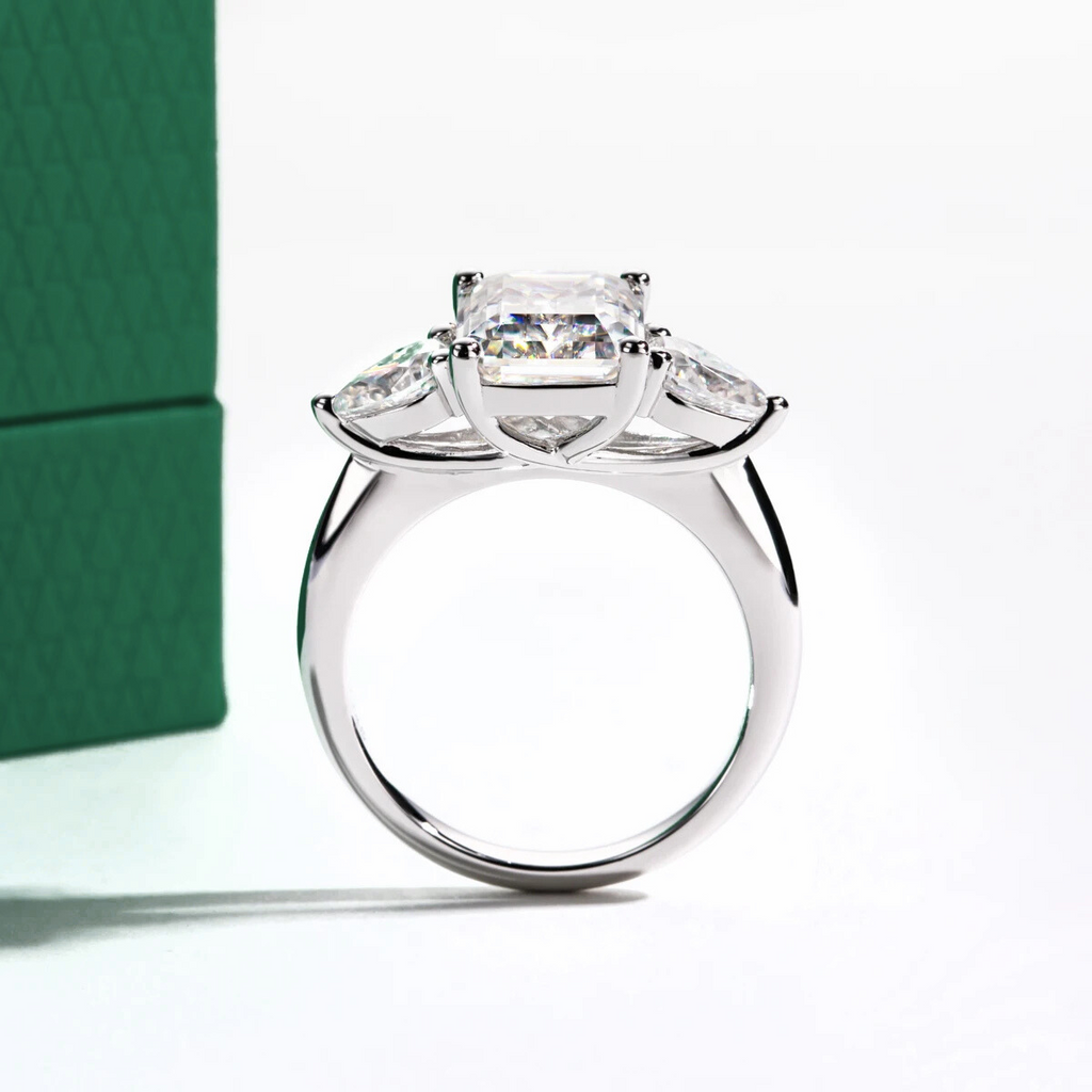 Anel solitário prata com lapidação quadrada e pedras transparentes ao lado de caixa verde