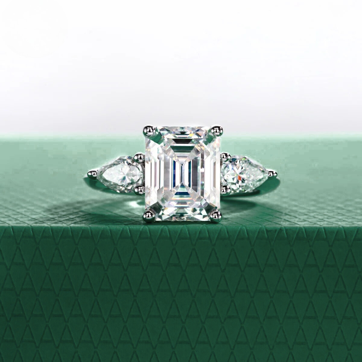 Anel solitário com lapidação esmeralda e moissanite central, pedras laterais em corte pera, base verde texturizada
