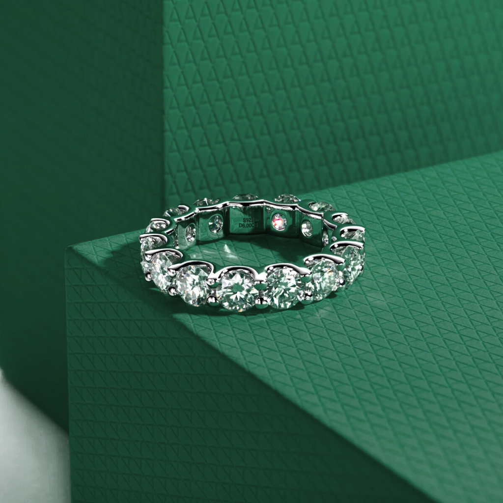 Aliança prateada com pedras brilhantes moissanite em fundo verde texturizado