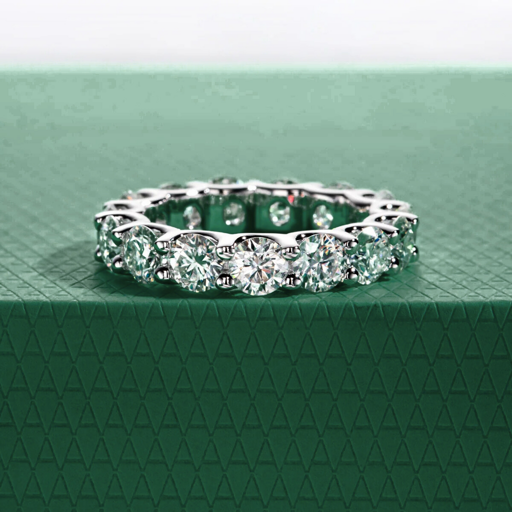 Aliança de moissanites brilhantes cravejada em metal prateado sobre fundo verde texturizado