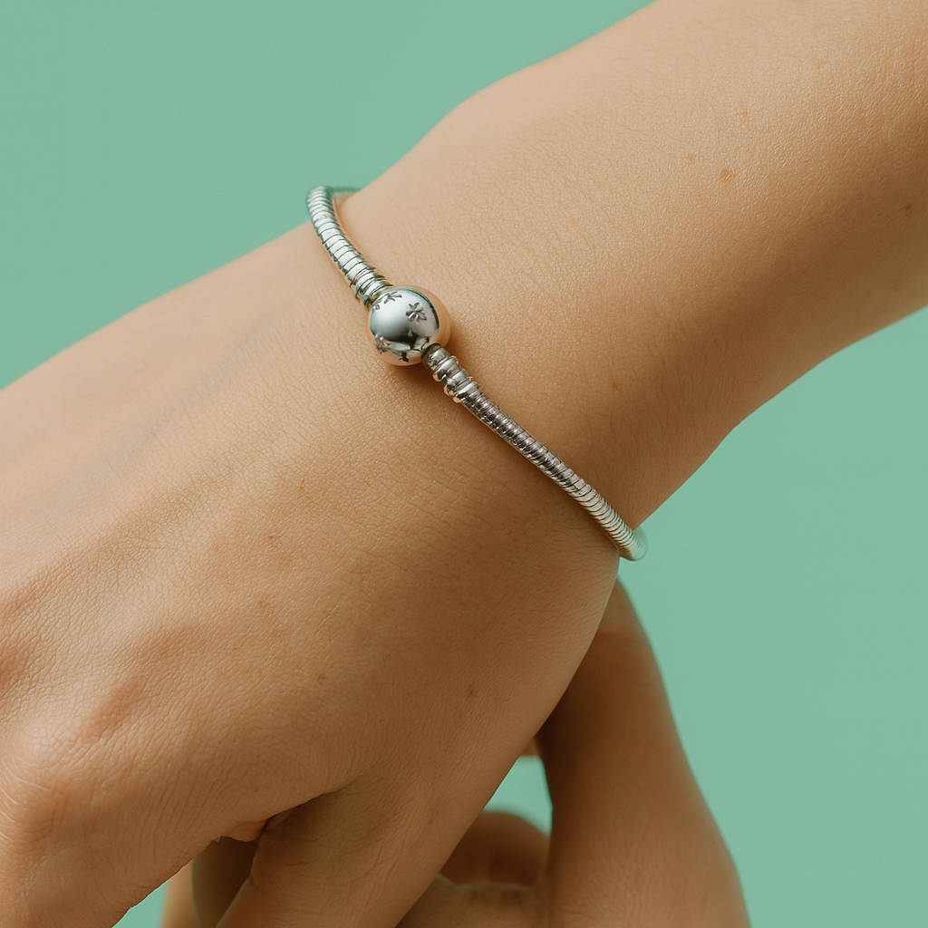 Pulseira de prata 925 com fecho arredondado gravado, usada no pulso feminino sobre fundo verde